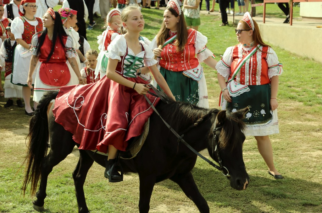 kislány ül a lovon népviseletben, a hagyományőrző szüreti felvonulás indulása előtt